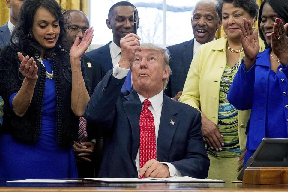 President Donald Trump holds up his pen after signing the Historically Black Colleges and Universities HBCU Executive Order, Tuesday, Feb. 28, 2017, in the Oval Office in the White House in Washington.